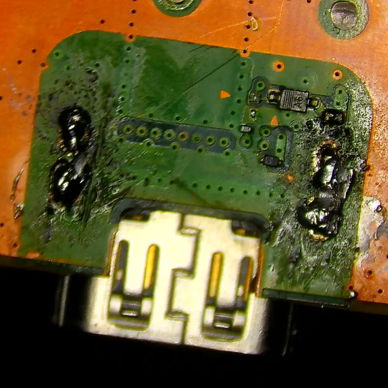 Wide view of PS5 motherboard HDMI port area showing extensive DIY repair damage and solder residue